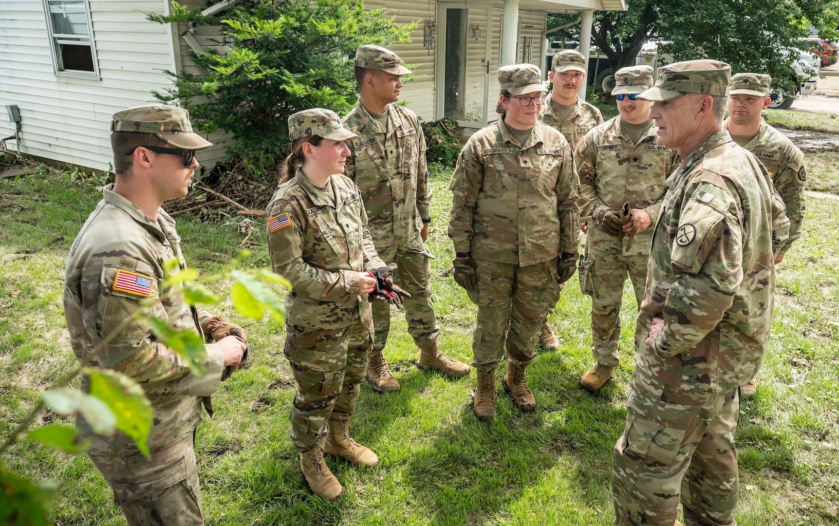 the adjutant general visiting soldiers conducting flood cleanup. everything covered in mud, soldiers in camo uniforms and safety vests.