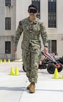 U.S. Navy Hospital Corpsman 3rd Class Jan Oseguera attempts to walk a straight line while wearing goggles simulating intoxication at the Annual Summer Safety Day event at Walter Reed National Military Medical Center on June 6, 2025. The event provides essential tips for staying safe and healthy during the summer months. (DOD photo by Roan Smith)