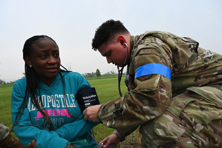 Airman 1st Class Thomas Sexton, 5th Medical Group (5MDG) medical technician, checks the blood pressure of Folashade Ajulo, 5MDG disease manager, at Minot Air Force Base, North Dakota, June 11, 2025. Sexton checked Ajulo’s blood pressure to sharpen his speed and accuracy with recording diagnostics during an emergency exercise. (U.S. Air Force photo by Airman 1st Class Anthony Ramey.)
