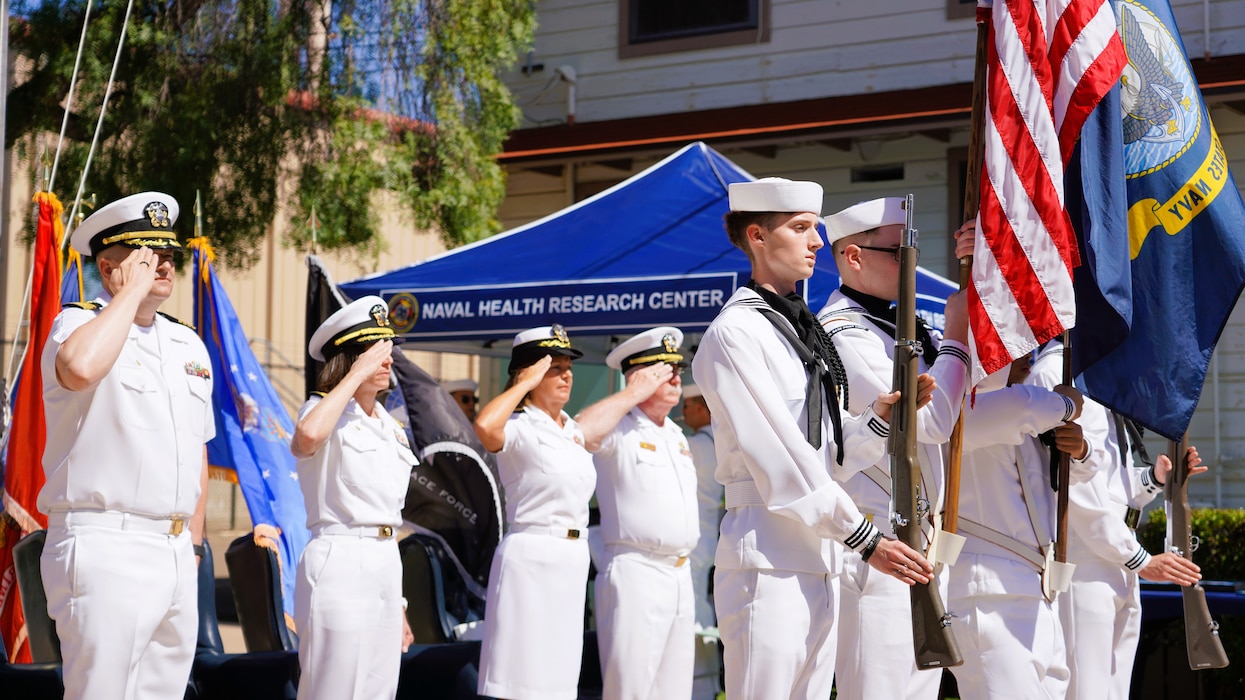 SAN DIEGO (June 17, 2025) Participants of Naval Health Research Center’s (NHRC) change of command salute as the Naval Base Point Loma Color Guard parade the colors during the opening of the ceremony. The change of command ceremony, presided over by Capt. Franca Jones, saw Capt. Eric Welsh relieved as commanding officer, NHRC by Capt. Kellie McMullen. NHRC, part of Navy Medicine Research & Development, supports Navy, Marine Corps, and joint U.S. warfighter health readiness and lethality with research and development that delivers high-value, high-impact solutions to the health and readiness challenges U.S. military population faces on the battlefield, at-sea, home and abroad. (U.S. Navy photo by Danielle Cazarez)