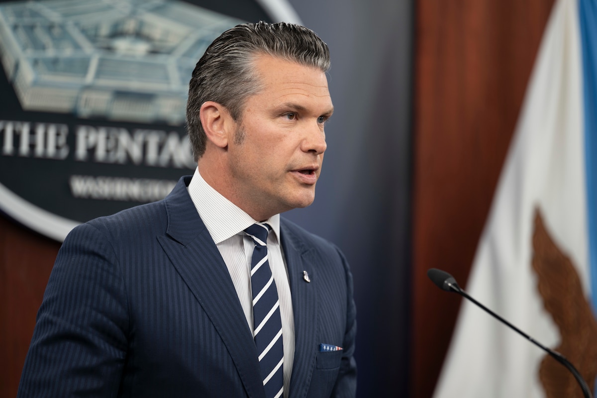 A man in a business suit is speaking into a microphone.