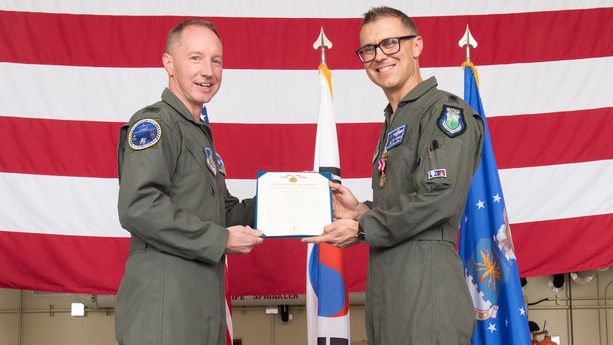 U.S. Air Force Lt. Col. Joseph Morrin, outgoing 51st Operations Support Squadron commander, right, receives the Meritorious Service Medal from Col. Kurt Distelzweig, left, 51st Operations Group commander, during a Change of Command ceremony at Osan Air Base, Republic of Korea, June 18, 2025.