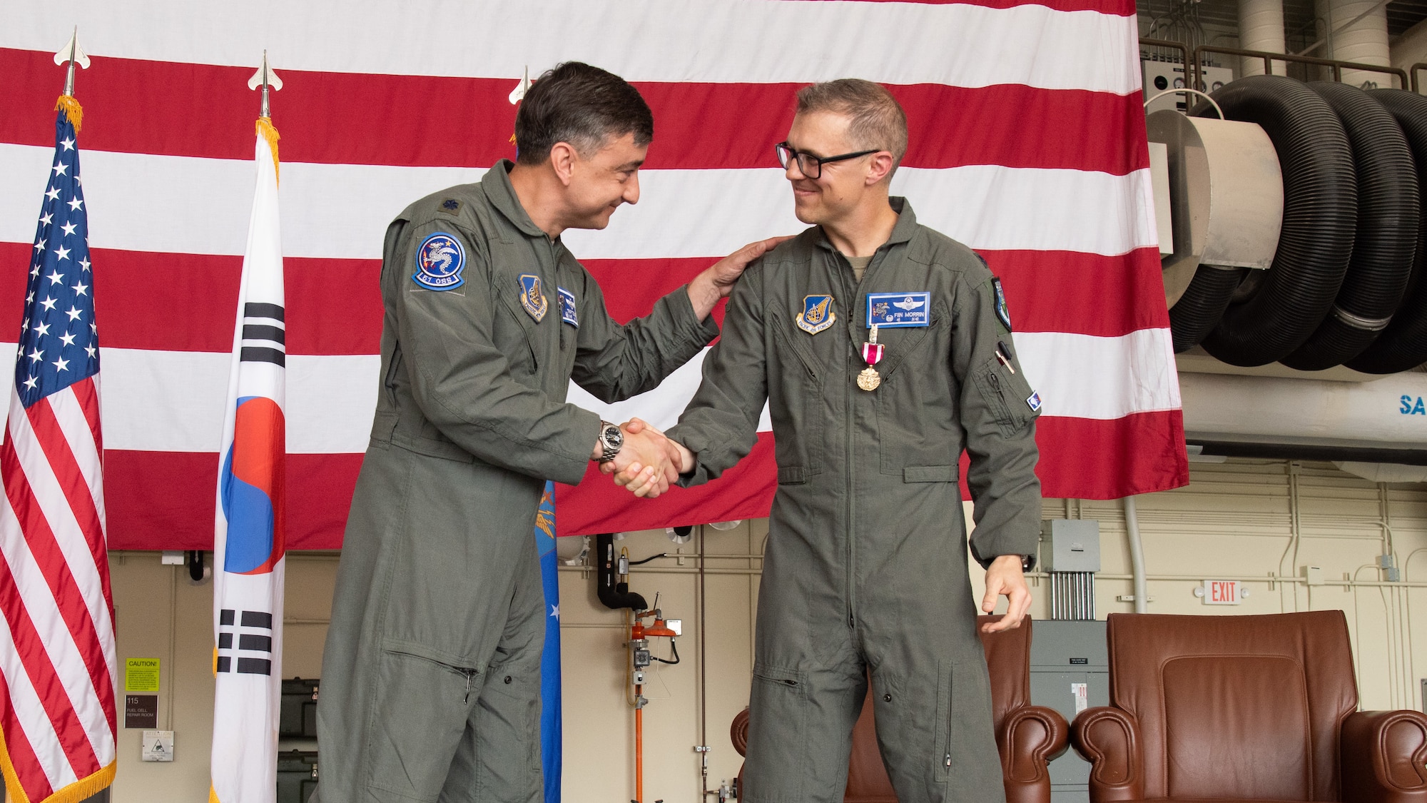 U.S. Air Force Lt. Col. Lance Tucker, incoming 51st Operations Support Squadron commander, left, shakes hands with Lt. Col. Joseph Morrin, outbound 51st OSS commander, right, at a Change of Command ceremony at Osan Air Base, Republic of Korea, June 18, 2025.