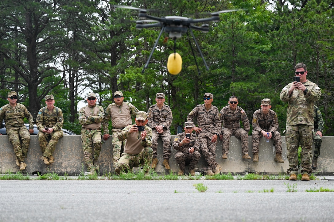 Soldiers from Central and South Asian countries watch as a U.S drone shows off its payload carrying capabilities at Joint Base Cape Cod, Massachusetts, June 19, 2025. during exercise Regional Cooperation 25. Regional Cooperation 25 is an annual, multinational U.S. Central Command sponsored command-post and field training exercise conducted by National Guard units in partnership with Central and South Asian nations. (U.S. Air Force photo by Staff Sgt. Colten Tessness)