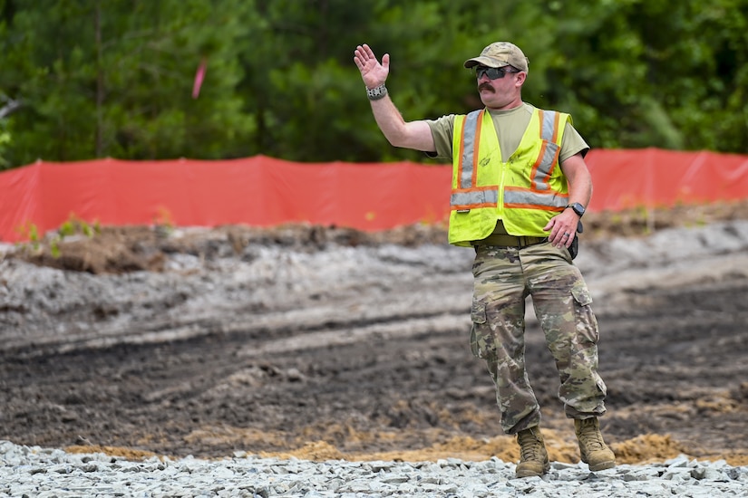 Pennsylvania Air National Guardsman, Master Sgt. Patrick Donohoe, assigned to the 171st Civil Engineer Squadron, directs a dump truck into place to receive a load of rock during a deployment for training, Assateague Island, Virginia, June 17, 2025. The 171st engineers are the 5th rotation of 8 during the deployment for training on the island. The DFT has provided engineers with unique training consistent with installing a runway while creating a new road for the Fish and Wildlife Service. (U.S. Air National Guard photo by Senior Master Sgt. Bryan Hoover)