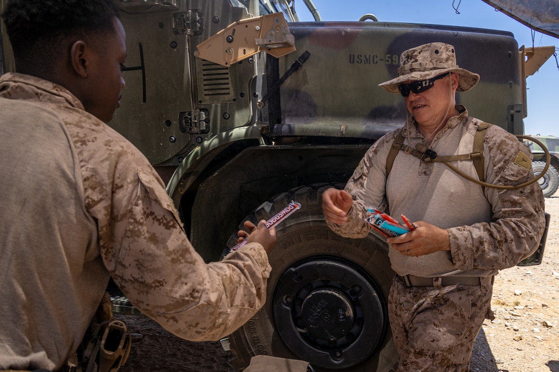 U.S. Navy Lt. Andrew Oswalt, a chaplain with Marine Wing Support Squadron 472, Marine Aircraft Group 49, 4th Marine Aircraft Wing, distributes popsicles to Marines during Integrated Training Exercise 3-25 (ITX 3-25) at Marine Corps Air Ground Combat Center, Twentynine Palms, California, June 10th, 2025. Chaplains develop force readiness by guiding Marines both spiritually and mentally in harsh environments. ITX is a critical Marine Air-Ground Task Force exercise for the Marine Forces Reserve’s training cycle, confirming unit readiness through live-fire and combined arms integration. (U.S. Marine Corps photo by Lance Cpl. Edward Spears)