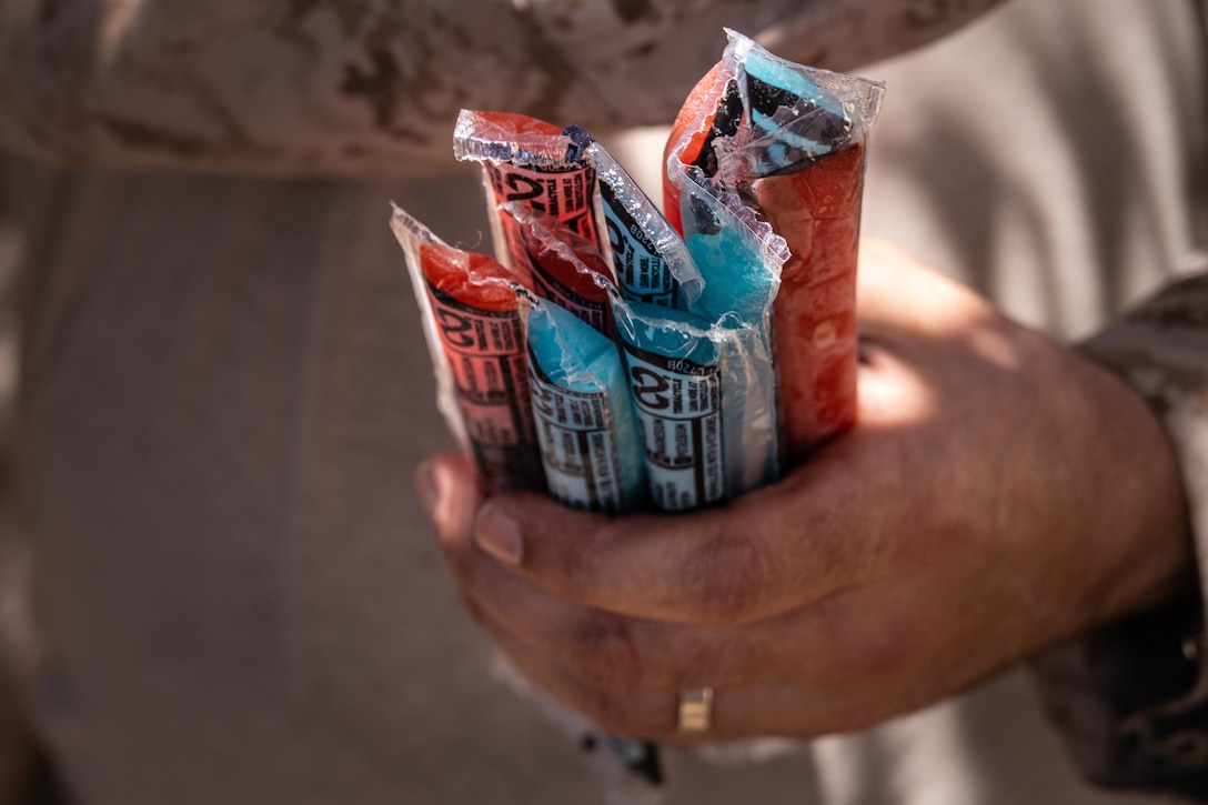 U.S. Navy Lt. Andrew Oswalt, a chaplain with Marine Wing Support Squadron 472, Marine Aircraft Group 49, 4th Marine Aircraft Wing, distributes popsicles during Integrated Training Exercise 3-25 (ITX 3-25) at Marine Corps Air Ground Combat Center, Twentynine Palms, California, June 10th, 2025. Chaplains develop force readiness by guiding Marines both spiritually and mentally in harsh environments. ITX is a critical Marine Air-Ground Task Force exercise for the Marine Forces Reserve’s training cycle, confirming unit readiness through live-fire and combined arms integration. (U.S. Marine Corps photo by Lance Cpl. Edward Spears)