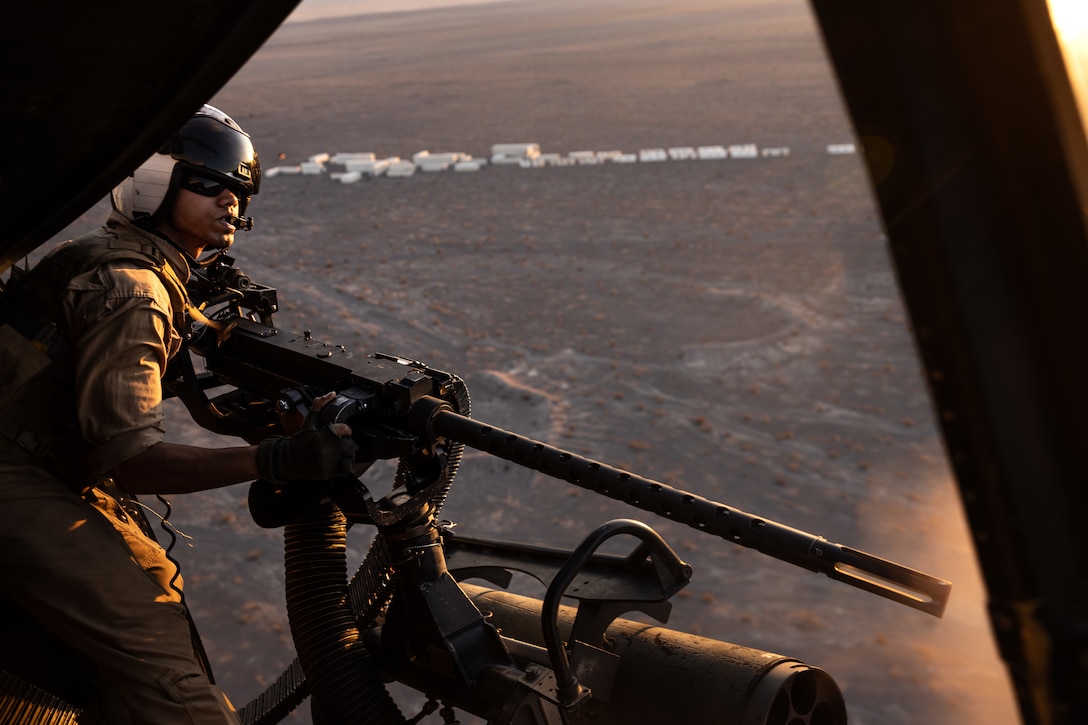 U.S. Marine Corps Cpl. Siddharth Butala, crew chief with Marine Light Attack Helicopter Squadron (HMLA) 773, 4th Marine Air Wing fire a machine gun at enemy combatants during Integrated Training Exercise 3-25 (ITX 3-25) at Marine Corps Air Ground Combat Center, Twentynine Palms, California, June 11th, 2025. ITX enhances Marines’ lethality by empowering leaders at every level to adapt, communicate, and execute dynamic movements in hostile environments. (U.S. Marine Corps photo by Lance Cpl. Edward Spears)