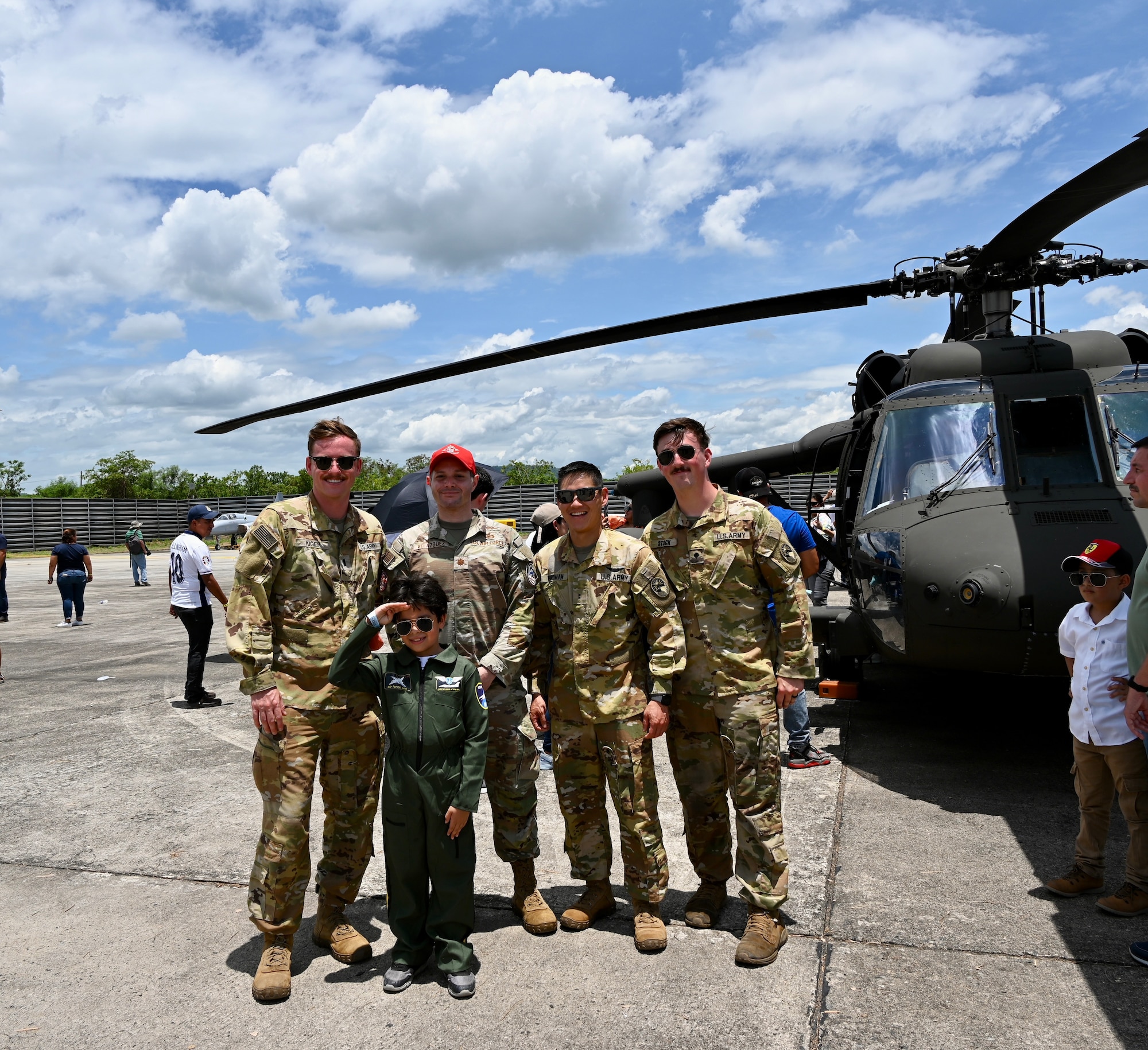 Pilots and aircrew from the 1-228th Aviation Regiment pose with a child dressed as a pilot during the Honduran Fuerza Aerea Air Show.