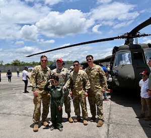 Pilots and aircrew from the 1-228th Aviation Regiment pose with a child dressed as a pilot during the Honduran Fuerza Aerea Air Show.