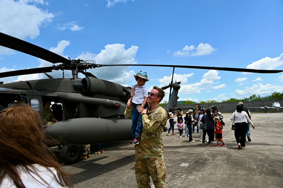 Lt Noah Kiger hoists a child on his shoulder in front of a UH-60 Black Hawk at the annual Fuerza Aerea air show in Honduras.