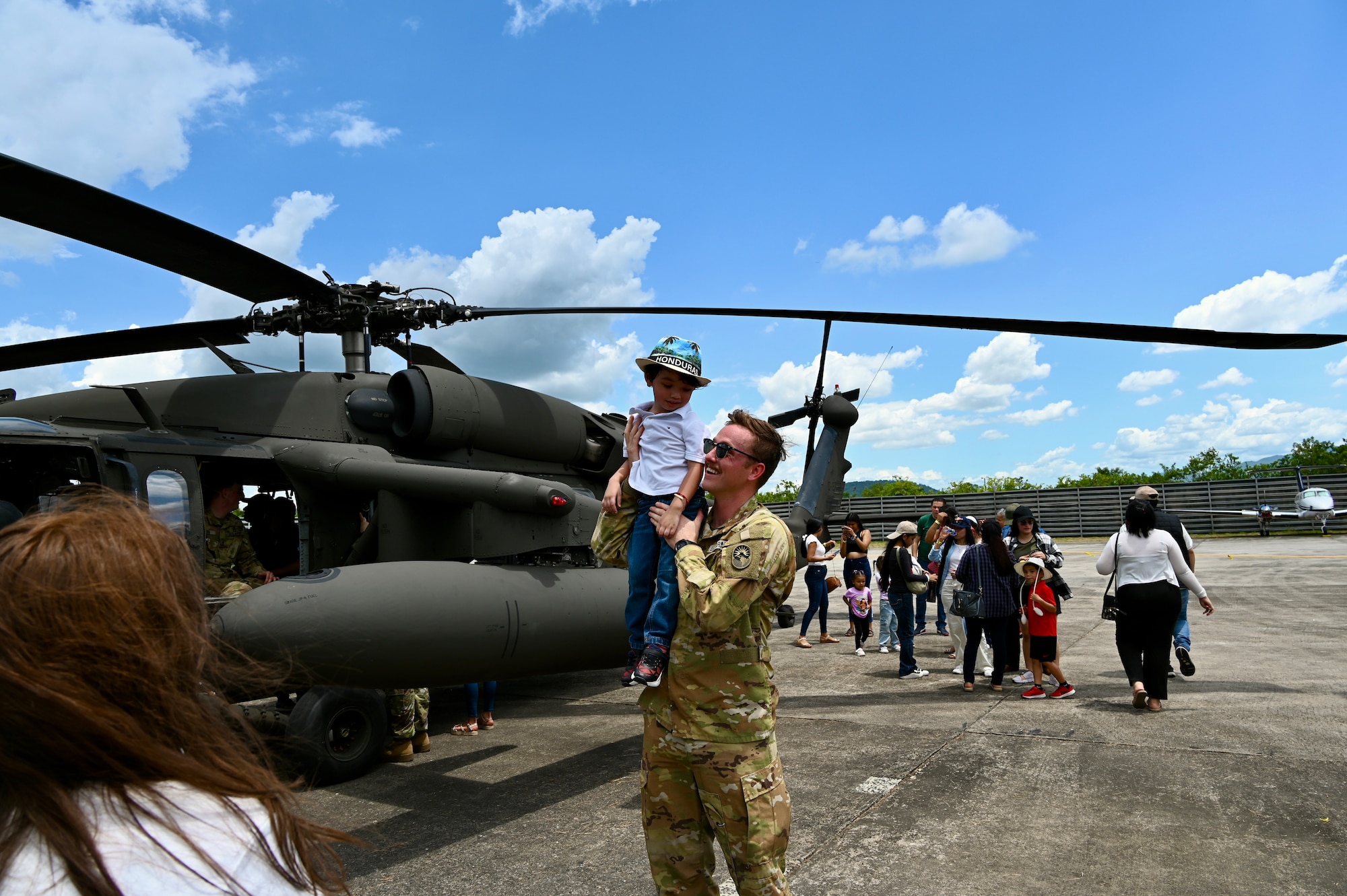 Lt Noah Kiger hoists a child on his shoulder in front of a UH-60 Black Hawk at the annual Fuerza Aerea air show in Honduras.
