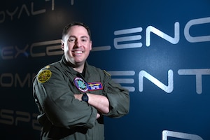 Man in flight suit folding his arms and smiling