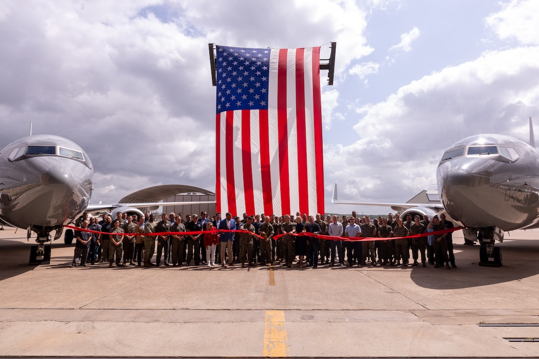 U.S. Marines with Marine Transport Squadron (VMR) 1 and civilians cut a ribbon after a ceremony recognizing the unit’s classification as a full operational capability squadron at Naval Air Station Joint Reserve Base Fort Worth, Texas, June 18, 2025.  VMR-1’s achievement of full operational capability with the C-40A aircraft, marks a significant milestone in squadron readiness and success. (U.S. Marine Corps photo by Cpl. Kanoa Thomas)