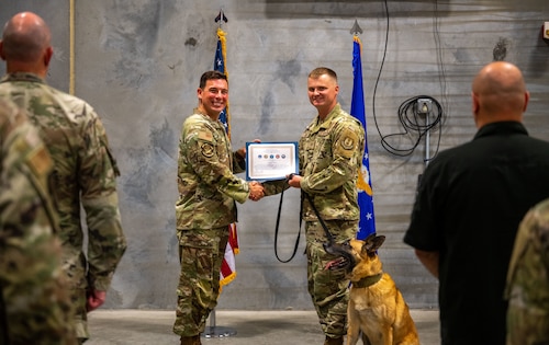 Lt. Col. Thomas Uhl, 88th Security Forces commander, recognizes Military Working Dog Misha and her accomplishments alongside her handler, Staff Sgt. Zachery Leist, June 10, 2025, at Wright-Patterson Air Force Base, Ohio. Misha worked more than 80 Secret Service missions, executed over 3,000 hours of anti-terrorism measures and delivered more than 100 canine demonstrations to the public. (U.S. Air Force photo by Jack Gardner)
