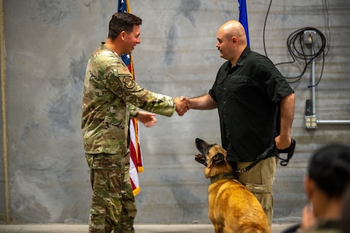Lt. Col. Thomas Uhl, 88th Security Forces commander, recognizes Military Working Dog Misha and her accomplishments alongside her former handler and adopter, Senior Airman Kyle Runk, June 10, 2025, at Wright-Patterson Air Force Base, Ohio. Misha worked more than 80 Secret Service missions, executed over 3,000 hours of anti-terrorism measures and delivered more than 100 canine demonstrations to the public. (U.S. Air Force photo by Jack Gardner)