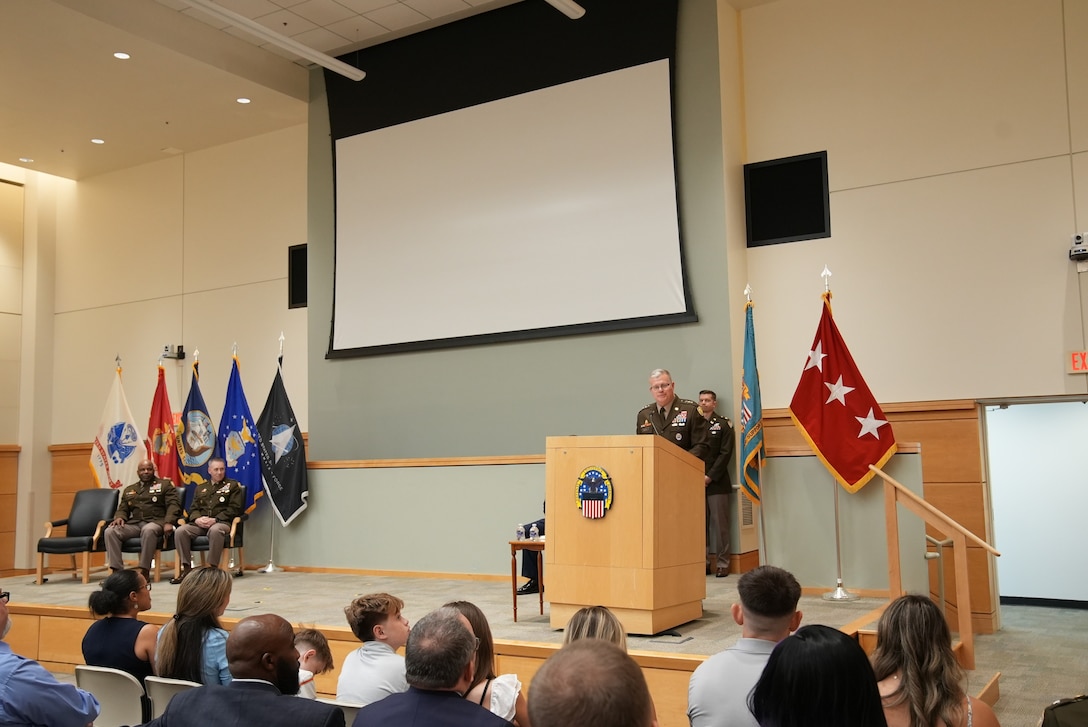 man in uniform stands at podium with audience in front of him