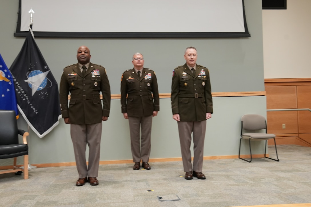 three men in uniform stand on stage
