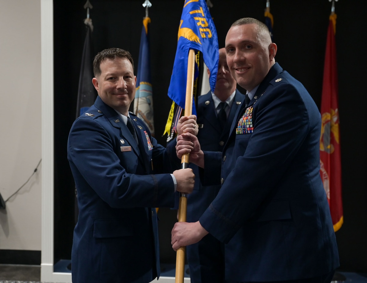 U.S. Air Force Col. Jason Gerber, 17th Training Group commander, passes the guidon to Lt. Col. Christopher Cardinale, incoming 313th Training Squadron commander, during the change of command ceremony at the Powell Event Center, Goodfellow Air Force Base, Texas, June 18, 2025. Before joining the 313th TRS, Cardinale was a strategy mission manager for the Office of the Director of National Intelligence. (U.S. Air Force photo by Senior Airman Evelyn J. D’Errico)