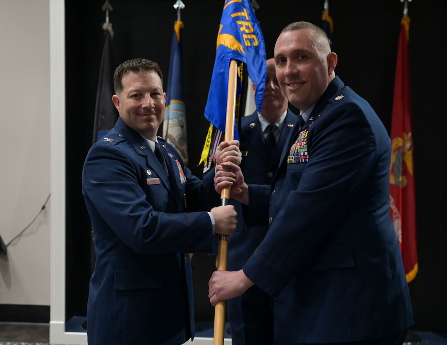 U.S. Air Force Col. Jason Gerber, 17th Training Group commander, passes the guidon to Lt. Col. Christopher Cardinale, incoming 313th Training Squadron commander, during the change of command ceremony at the Powell Event Center, Goodfellow Air Force Base, Texas, June 18, 2025. Before joining the 313th TRS, Cardinale was a strategy mission manager for the Office of the Director of National Intelligence. (U.S. Air Force photo by Senior Airman Evelyn J. D’Errico)