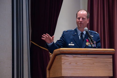 An Airman behind a podium addressing attendees in a speech