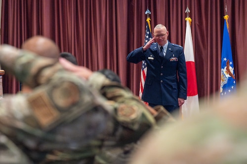 One Airman on stage saluting a formation