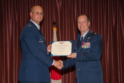 Two Airmen holding a certificate on stage