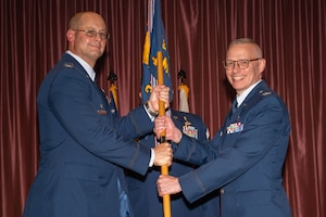 Airmen holding a flag together on stage