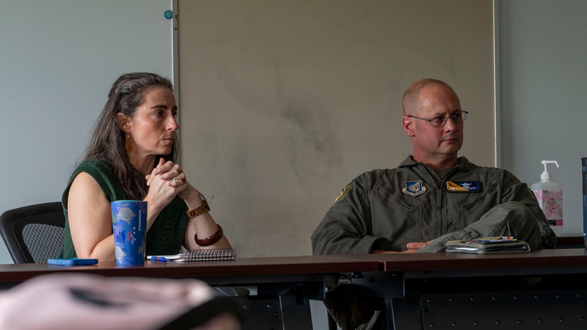 U.S. Air Force Col. Richard McElhaney, 374th Airlift Wing commander, and his spouse Carolyn McElhaney, sit at a table listen to attendees.