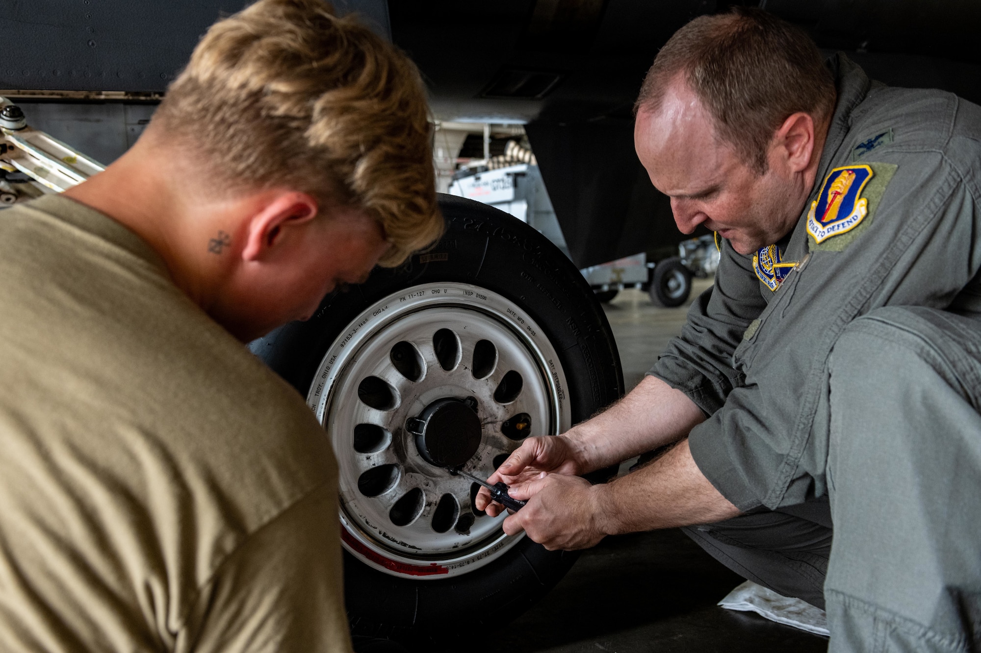 U.S. Air Force Col. Matthew Kenkel, right, 35th Fighter Wing deputy commander, and Senior Airman Derek Johnson, 14th Fighter Generation Squadron F-16 Fighting Falcon assistant dedicated crew chief, unfastens a wheel from an F-16 during a brake pad change.