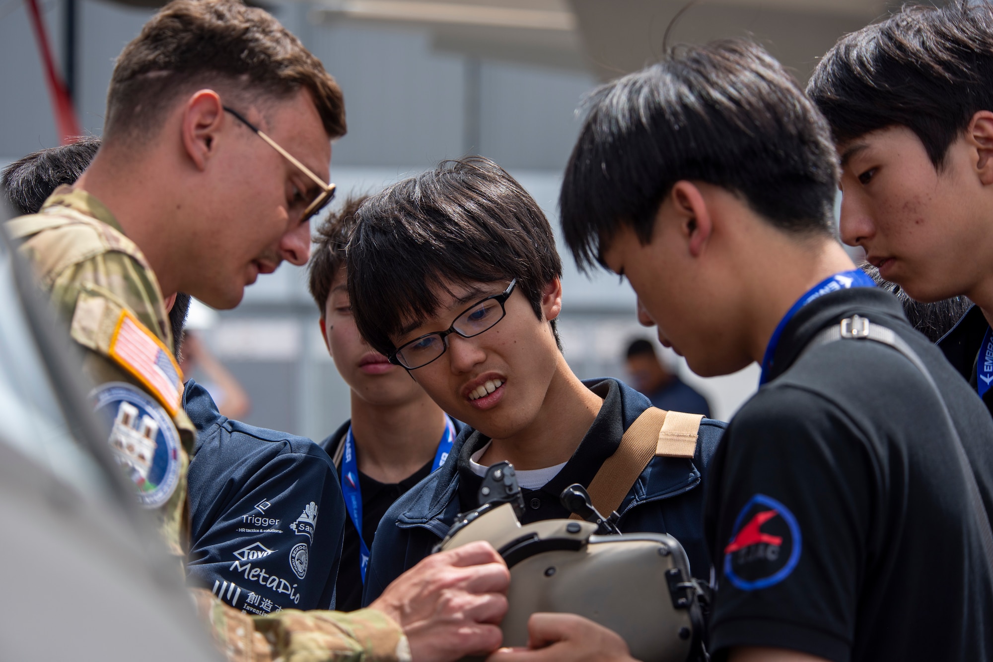 Service member showing students a flight helmet.