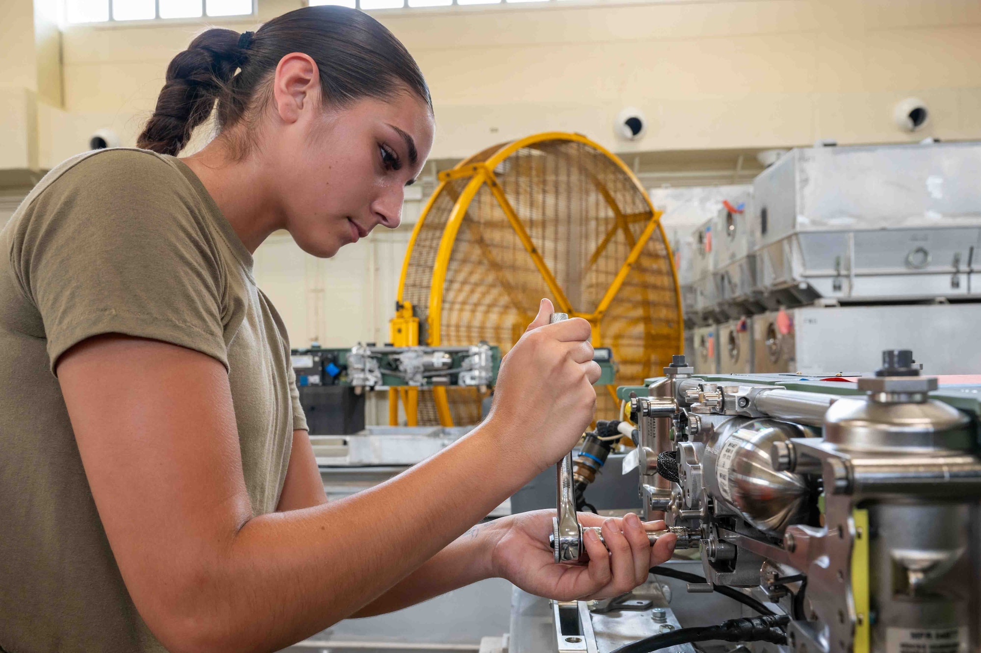 service member uses a tool on a machine