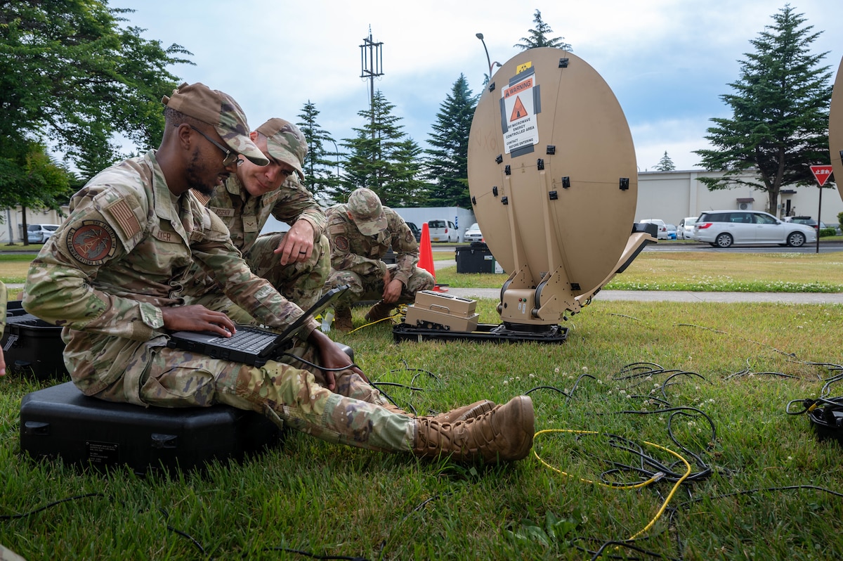 U.S. Air Force Airman 1st Class Jamari Hooker, left, and Airman 1st Class Milen Arsenov, 35th Communications Squadron radio frequency system transmission technicians, troubleshoot a terminal connected to a Hawkeye III Lite satellite system Rapid Response Communications Kit at Misawa Air Base, Japan, June 24, 2025.
