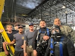 Naval Undersea Warfare Center (NUWC) Keyport Division’s Dive team poses for a photo with Naval Surface Warfare Center Carderock Division’s (NSWCCD)Commanding Officer at the David Taylor Model Basin at West Bethesda, Md. From May 27 to May 31, 2025, the six divers hand-removed 10-tons of corroded steel from the test basin floor in preparation for the 18th International Submarine Races, hosted by Carderock.