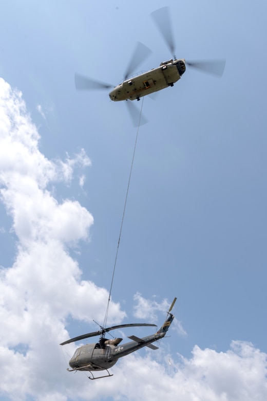 A CH-47 Chinook helicopter from 2-104th General Support Aviation Battalion, 28th Expeditionary Combat Aviation Brigade airlifts a decommissioned UH-1 “Huey” helicopter from the top Blue Mountain near Fort Indiantown Gap, Pennsylvania, to the installation on June 20, 2025. (Pennsylvania National Guard photo by Wayne V. Hall)