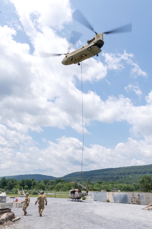 A CH-47 Chinook helicopter from 2-104th General Support Aviation Battalion, 28th Expeditionary Combat Aviation Brigade airlifts a decommissioned UH-1 “Huey” helicopter from the top Blue Mountain near Fort Indiantown Gap, Pennsylvania, to the installation on June 20, 2025. (Pennsylvania National Guard photo by Wayne V. Hall)