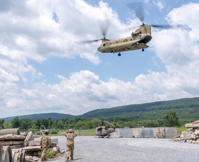 A CH-47 Chinook helicopter from 2-104th General Support Aviation Battalion, 28th Expeditionary Combat Aviation Brigade airlifts a decommissioned UH-1 “Huey” helicopter from the top Blue Mountain near Fort Indiantown Gap, Pennsylvania, to the installation on June 20, 2025. (Pennsylvania National Guard photo by Wayne V. Hall)