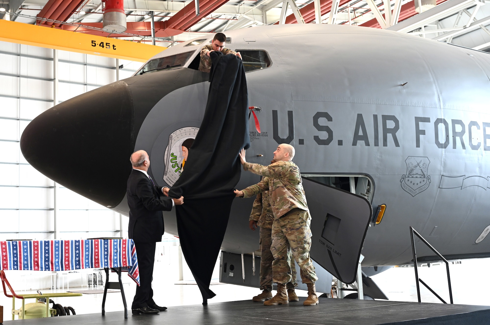 U.S. Air Force Senior Airman Sebastian Miskimmin, top, removes a cover to unveil the 100th Air Refueling Wing’s latest legacy nose art addition, “Just-A-Snappin,” assisted by Steve Crosby, left, son of then-1st Lt. Harry Crosby, World War II and 100th Bomb Group navigator, and Lt. Col. Scott Engman, 100th Logistics Readiness Squadron commander, during a ceremony at RAF Mildenhall, England, June 9, 2025. The nose art, designed by Gary Rogers, 100th ARW Public Affairs graphic designer, pays tribute to Crosby and the rest of the aircrew who flew together on the B-17 Flying Fortress, Just-A-Snappin, on the Bremen mission over Germany in October 1943. (U.S. Air Force photo by Karen Abeyasekere)