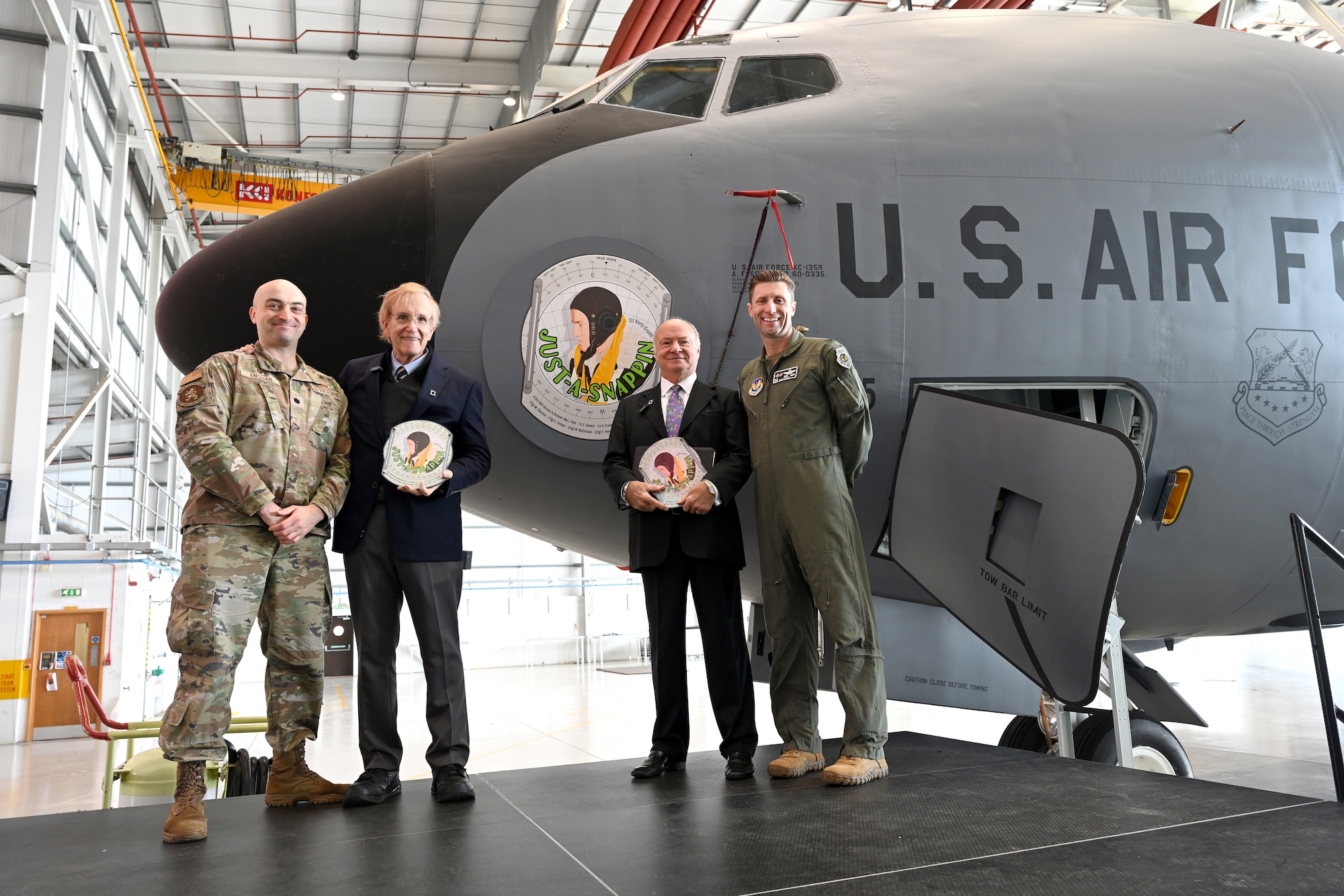 Left to right, U.S. Air Force Lt. Col. Scott Engman, 100th Logistics Readiness Squadron commander; Jim Blakely, son of World War II and 100th Bomb Group pilot, then-1st Lt. Everett Blakely; Steve Crosby, son of 100th BG navigator, then-1st Lt Harry Crosby, and Col. Ryan Garlow, 100th Air Refueling Wing commander, pose for a photo with the 100th ARW’s latest legacy nose art, “Just-A-Snappin,” during the nose art ceremony at RAF Mildenhall, England, June 9, 2025. The Just-A-Snappin nose art has now been added to a KC-135 Stratotanker and focuses on the profile of Harry Crosby, also incorporating a background of a navigator’s dead-reckoning computer, and the names of the entire crew who flew the Bremen mission over Germany in October 1943. (U.S. Air Force photo by Karen Abeyasekere)