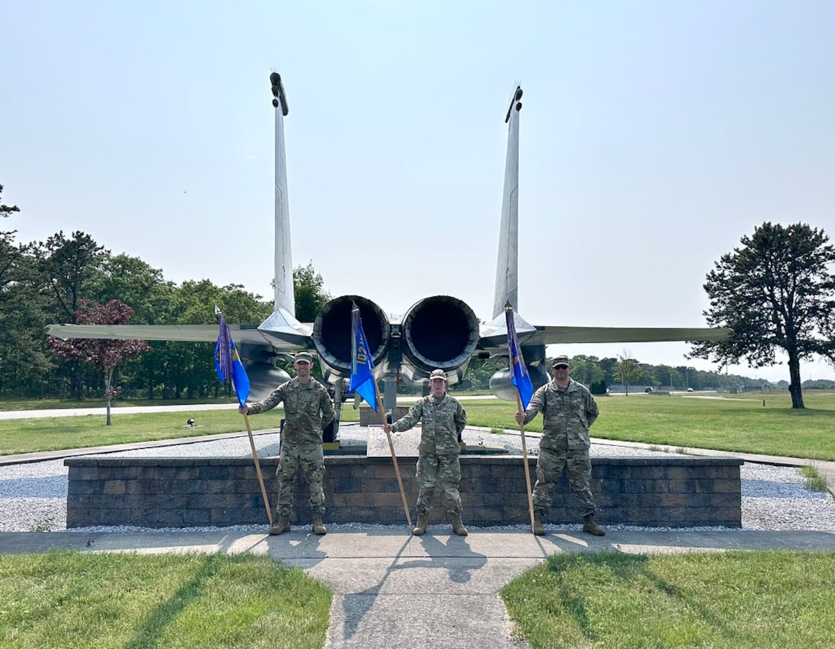 A group of Airmen, in a formation outside, pay respects to the American flag.
