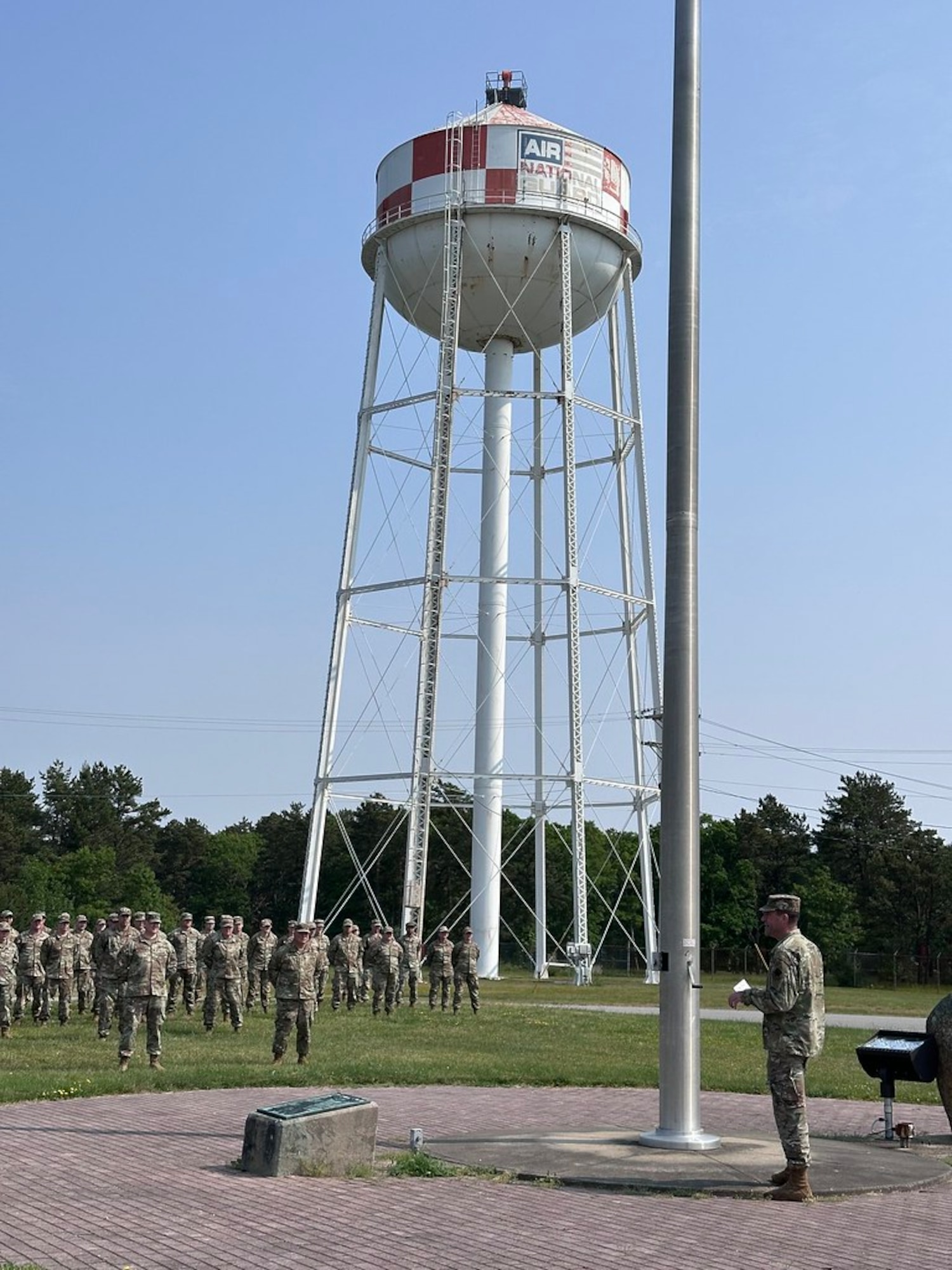 A group of Airmen, in a formation outside, pay respects to the American flag.