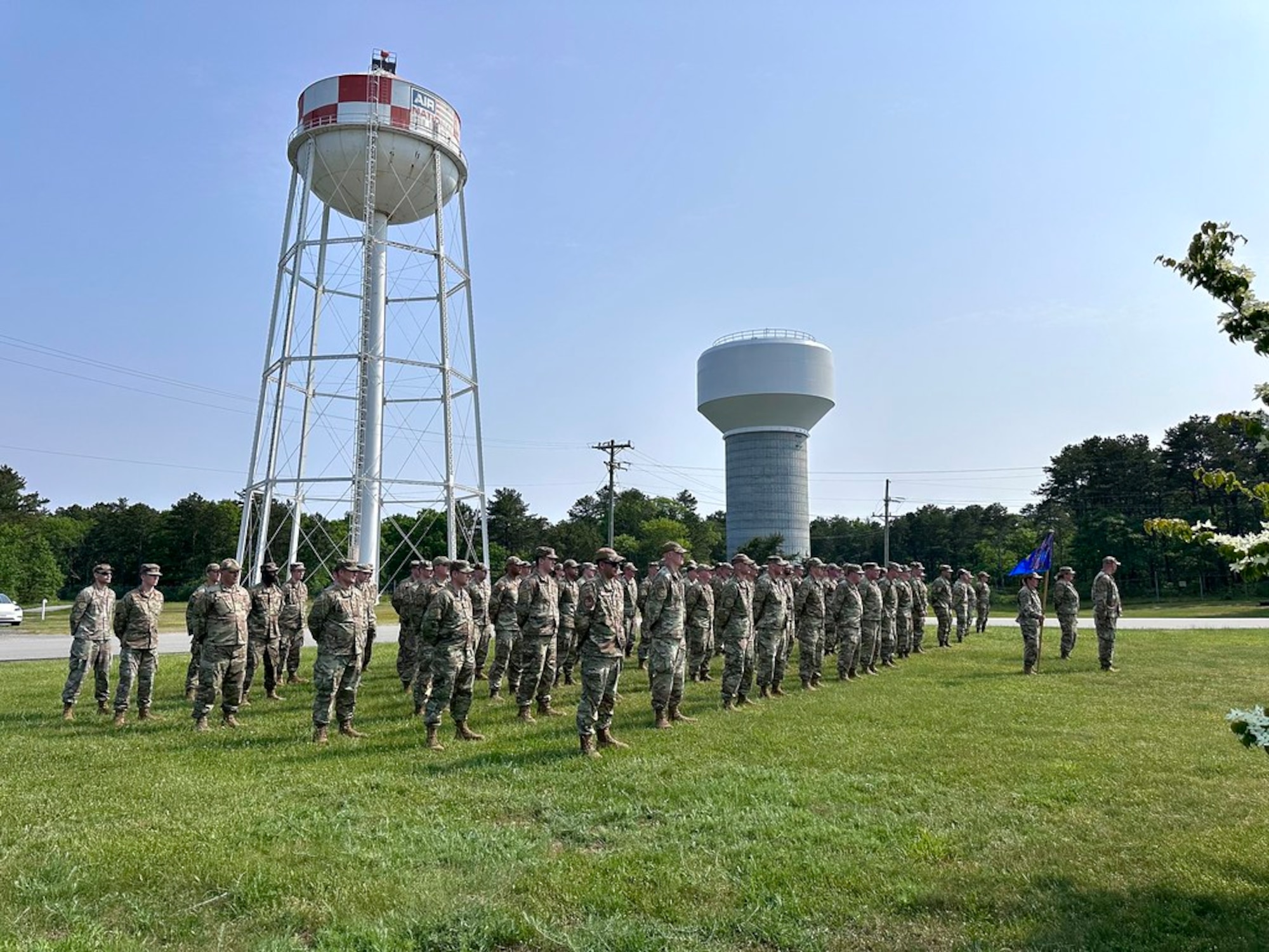 A group of Airmen, in a formation outside, pay respects to the American flag.