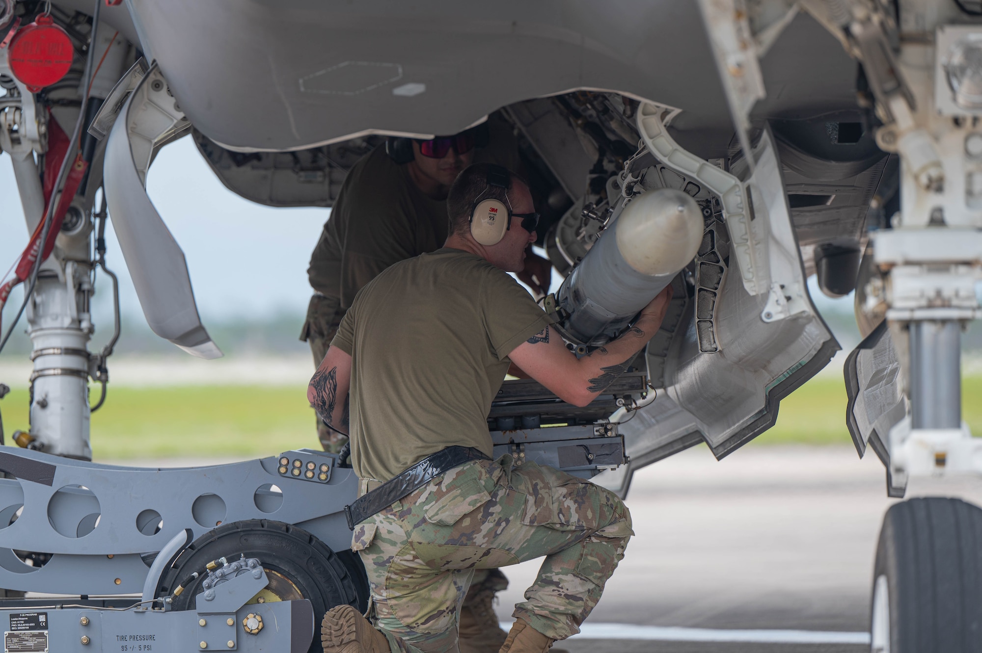 Two Airmen load munitions onto an F-35