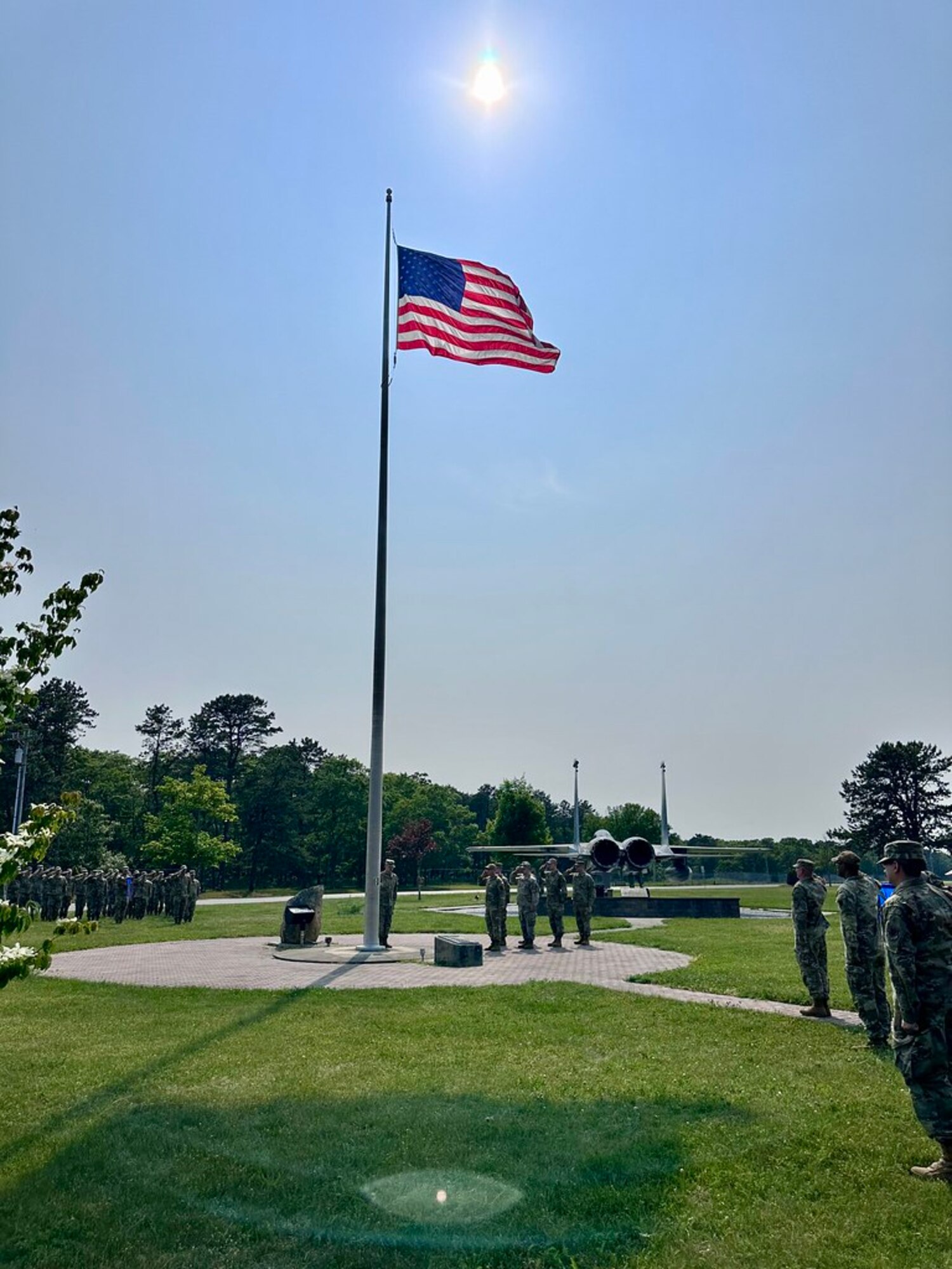 A group of Airmen, in a formation outside, pay respects to the American flag.