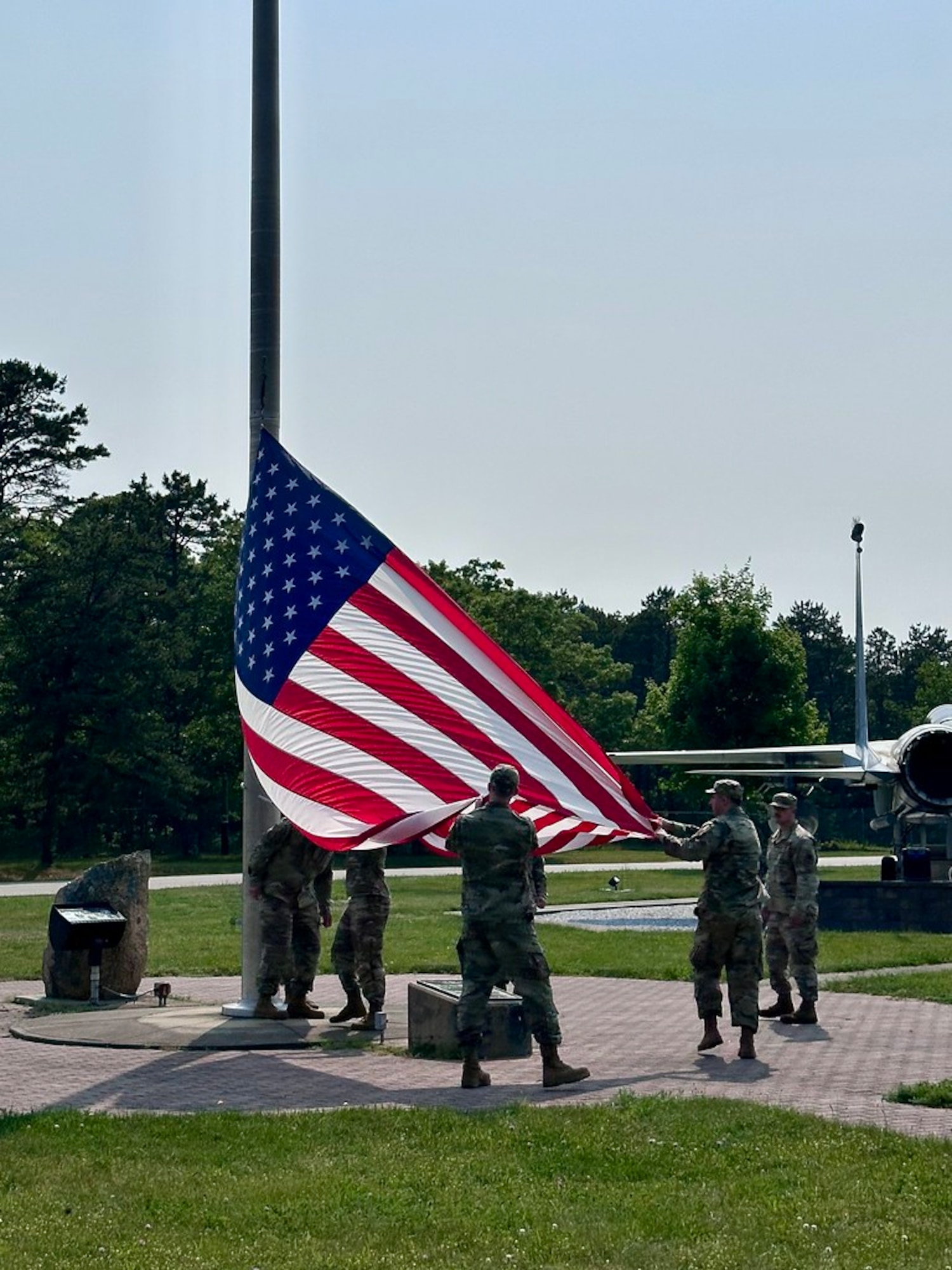 A group of Airmen, in a formation outside, pay respects to the American flag.