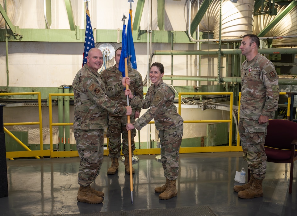 Lt. Col. Rachel Chrash, second from right, takes the guidon from 804th Test Group Commander Col. Jason Vap, left, to assume command of the 718th Test Squadron during a Change of Command ceremony June 18, 2025, at Arnold Air Force Base, Tenn., headquarters of Arnold Engineering Development Complex. Also pictured is outgoing 718 TS commander Lt. Col. Bradley Breaux, right. (U.S. Air Force photo by Keith Thornburgh)