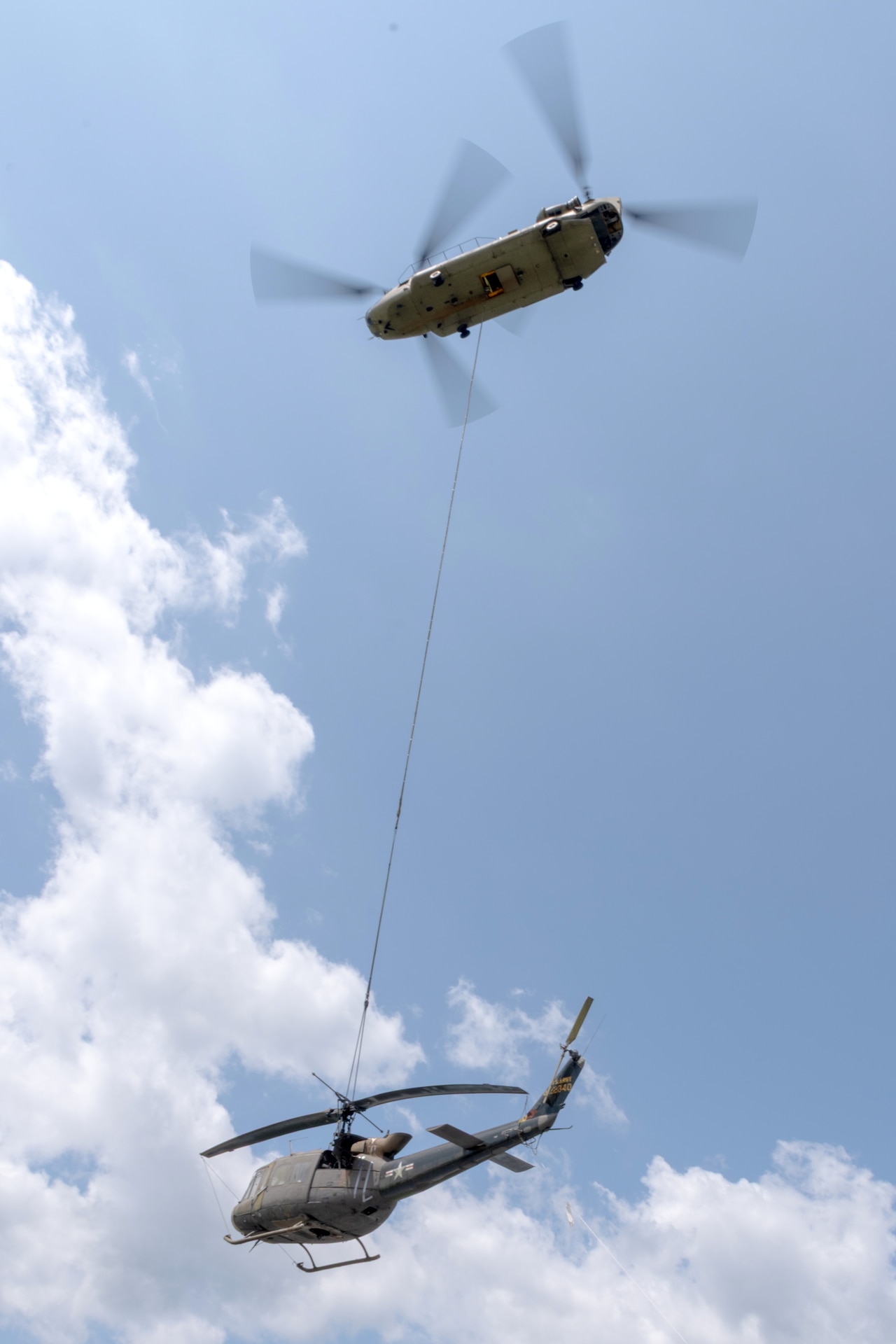 A CH-47 Chinook helicopter from 2-104th General Support Aviation Battalion, 28th Expeditionary Combat Aviation Brigade airlifts a decommissioned UH-1 “Huey” helicopter from the top Blue Mountain near Fort Indiantown Gap, Pennsylvania, to the installation on June 20, 2025. (Pennsylvania National Guard photo by Wayne V. Hall)