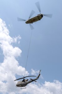 A CH-47 Chinook helicopter from 2-104th General Support Aviation Battalion, 28th Expeditionary Combat Aviation Brigade airlifts a decommissioned UH-1 “Huey” helicopter from the top Blue Mountain near Fort Indiantown Gap, Pennsylvania, to the installation on June 20, 2025. (Pennsylvania National Guard photo by Wayne V. Hall)