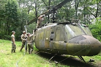 Soldiers from the 2-104th General Support Aviation Battalion, 28th Expeditionary Combat Aviation Brigade prepare a decommissioned UH-1 “Huey” helicopter to be air-lifted from the top of a mountain near Fort Indiantown Gap, Pennsylvania, to the installation June 20, 2025. (Pennsylvania National Guard photo by Brad Rhen)