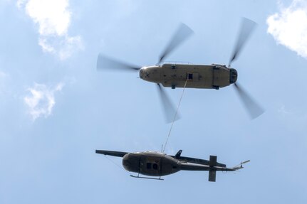 A CH-47 Chinook helicopter from 2-104th General Support Aviation Battalion, 28th Expeditionary Combat Aviation Brigade airlifts a decommissioned UH-1 “Huey” helicopter from the top Blue Mountain near Fort Indiantown Gap, Pennsylvania, to the installation on June 20, 2025. (Pennsylvania National Guard photo by Wayne V. Hall)
